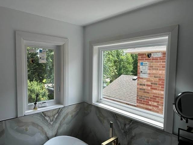 Corner bathroom casement and picture windows with white molding above a soaking tub.